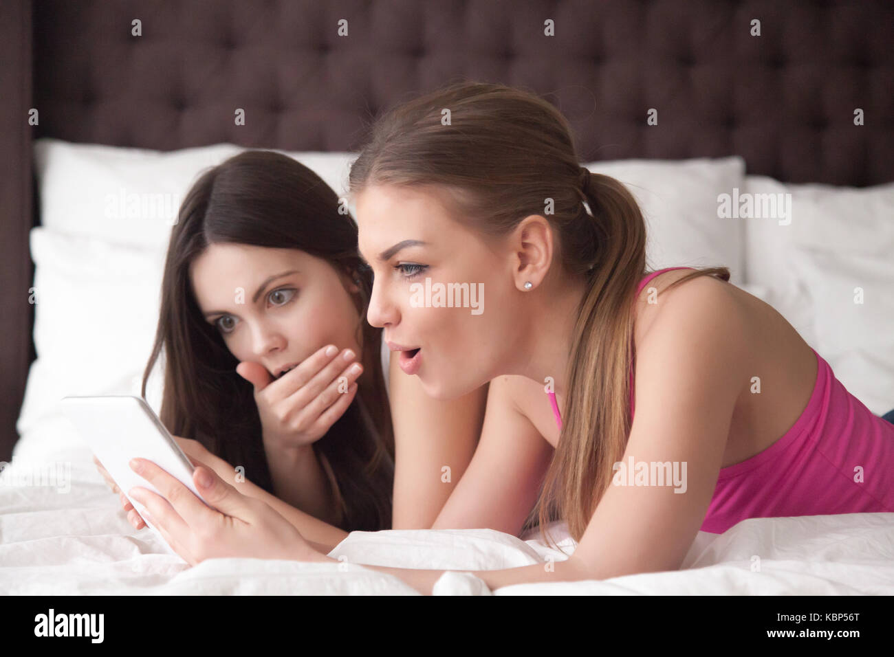 Two girlfriends looking at electronic tablet with shocked expres Stock Photo