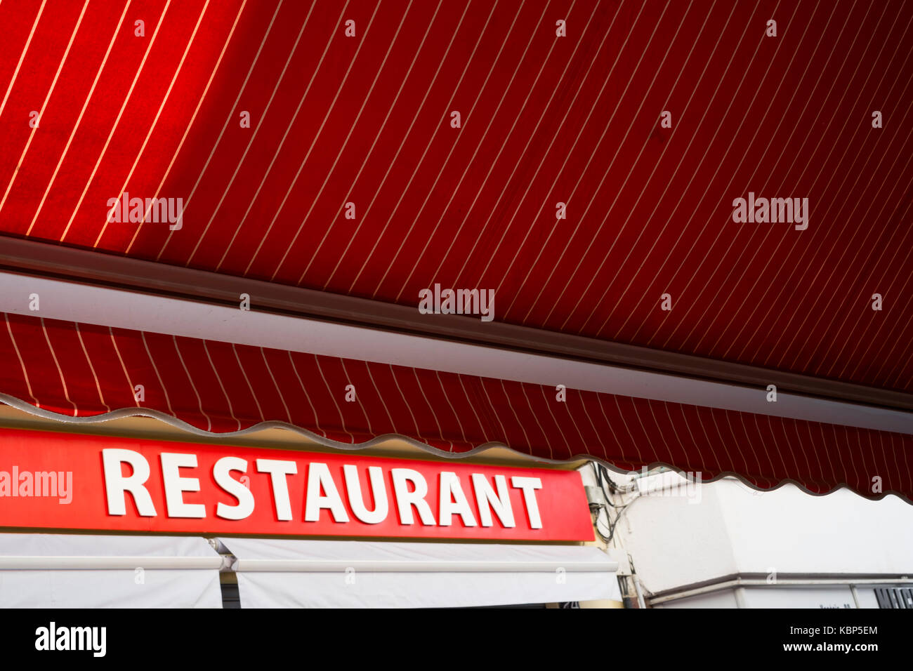 A red canopy opposite a red restaurant sign in Lloret de Mar, Spain Stock Photo