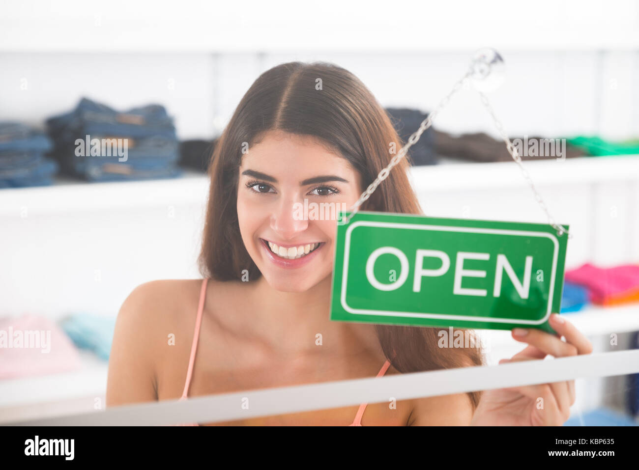 Portrait of smiling female owner holding open sign in clothing store Stock Photo