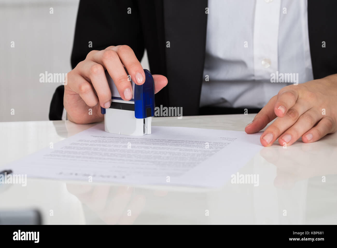 Cropped image of young businesswoman stamping contract document at office desk Stock Photo