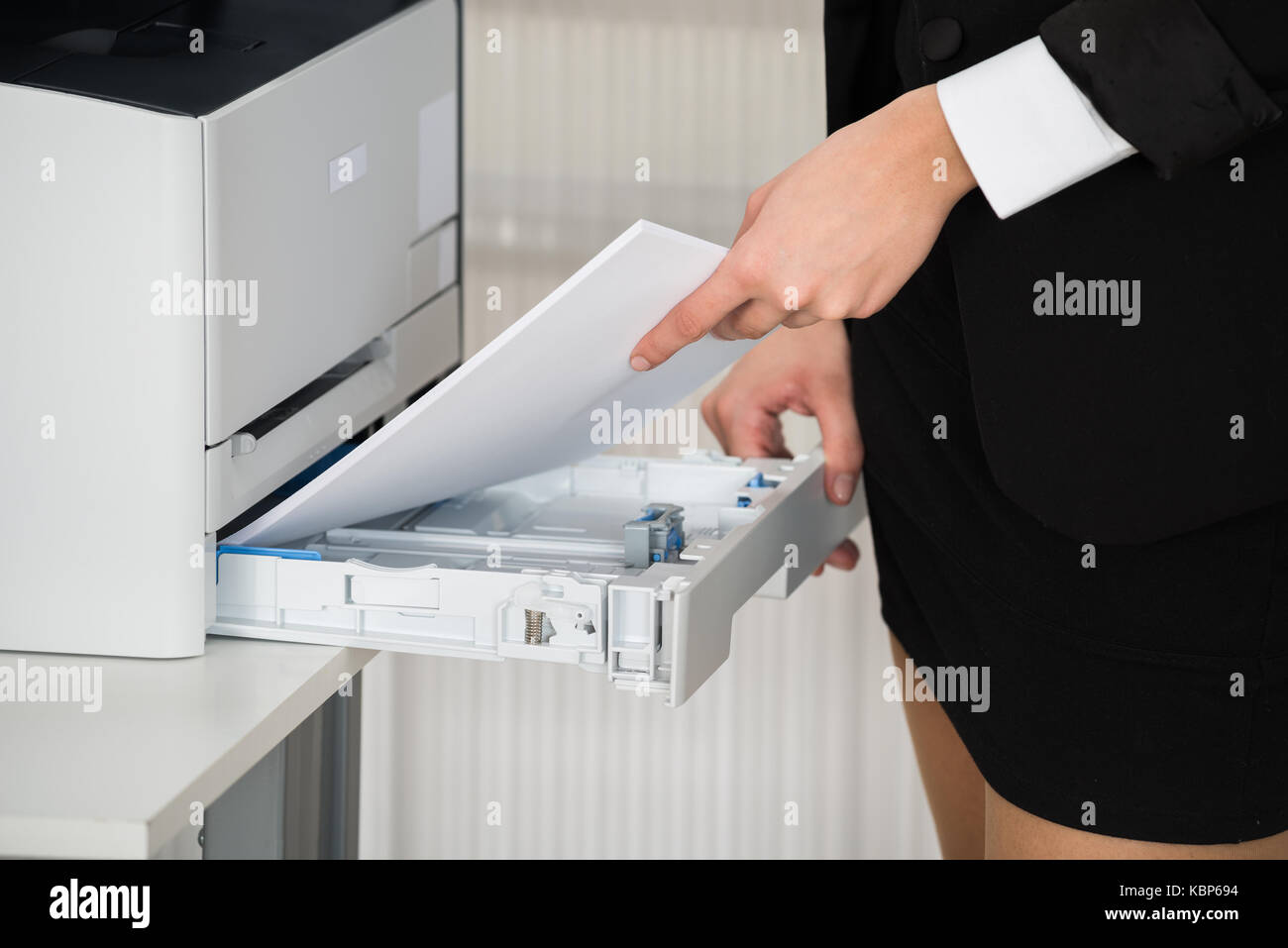 Midsection of businesswoman inserting papers in photocopy machine at