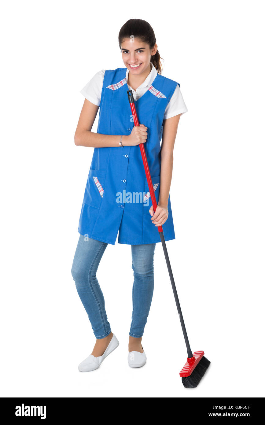 Full length portrait of happy female janitor sweeping on white background Stock Photo
