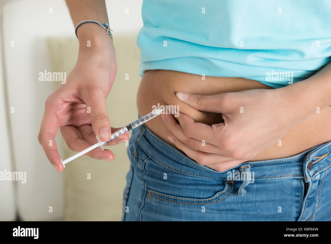 Midsection of diabetic young woman injecting stomach at home Stock Photo