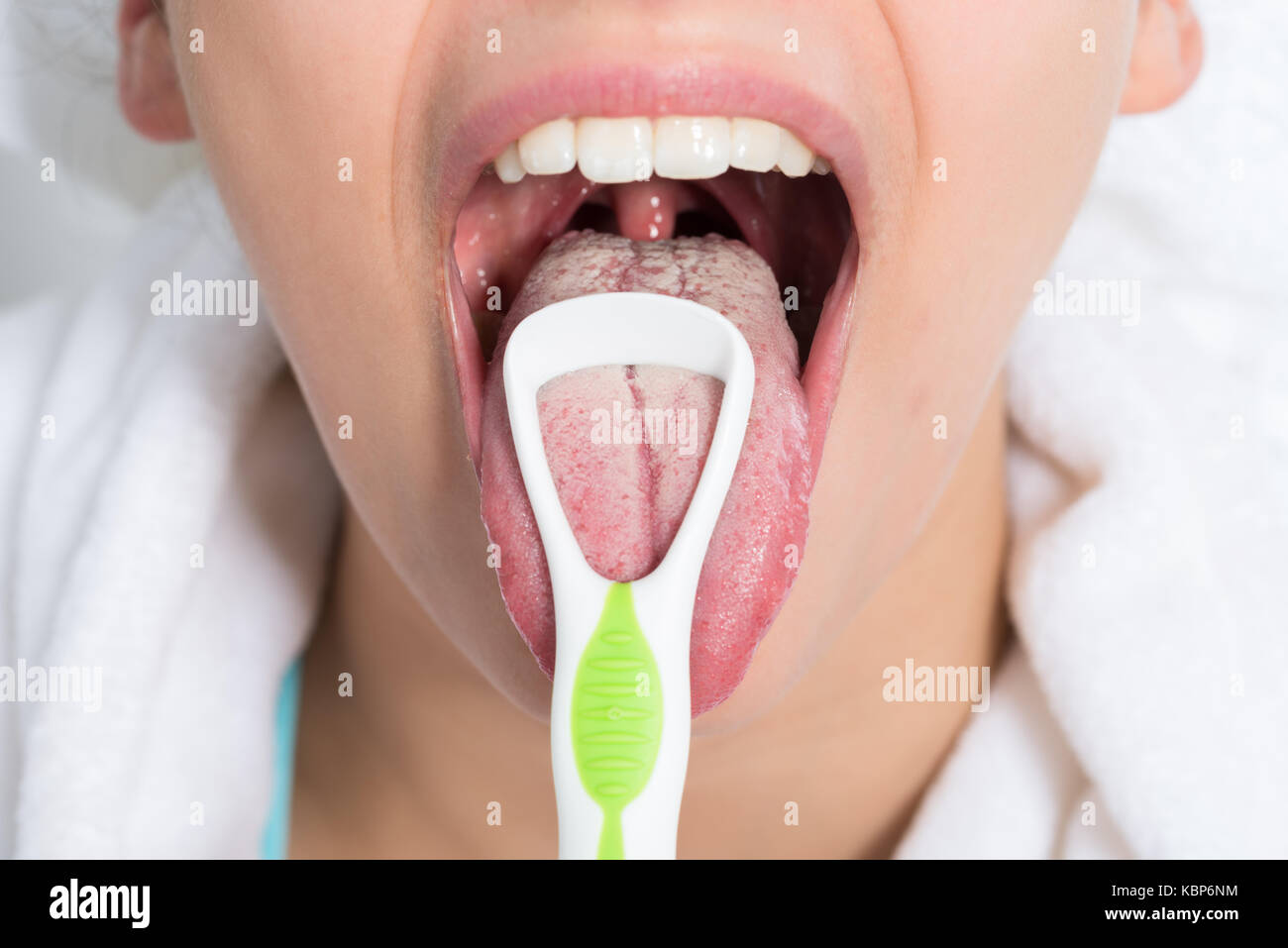 Closeup of young woman cleaning tongue with cleaner Stock Photo