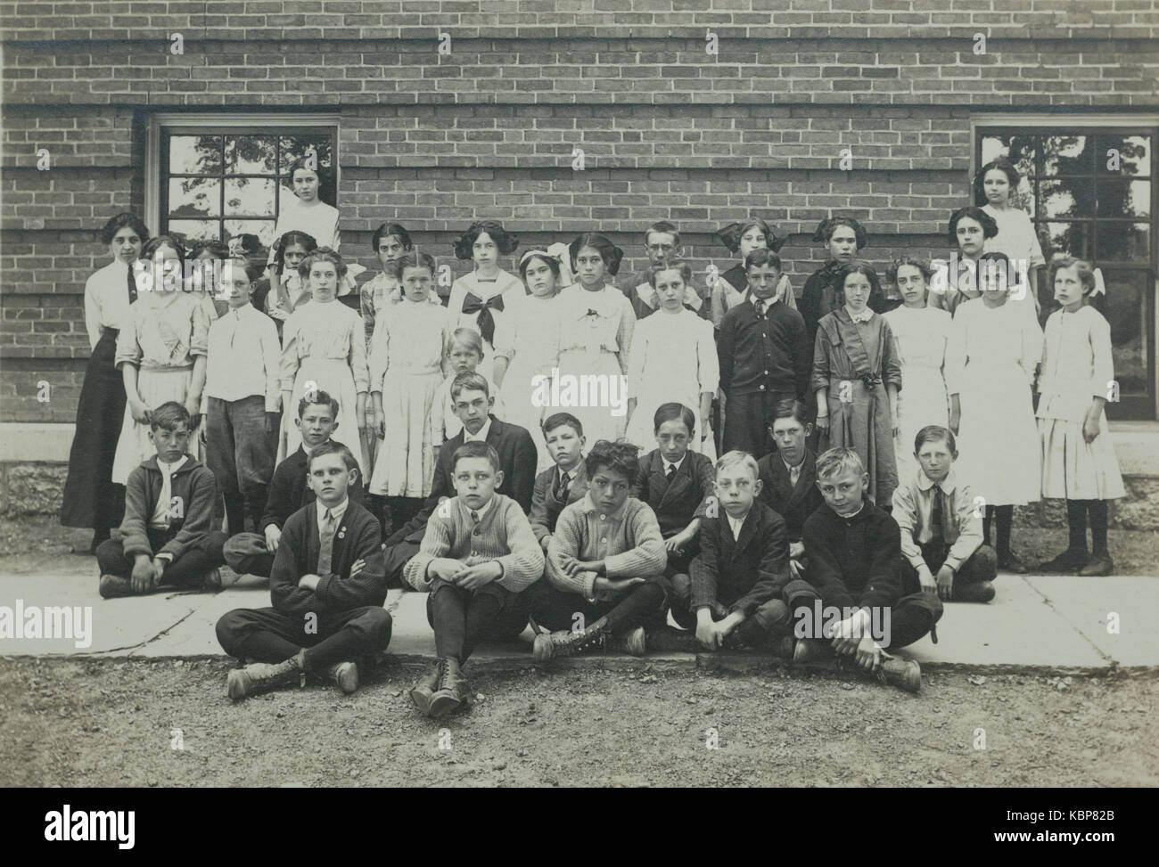 American archive monochrome photograph of class of school children and teacher, with school building, taken in the early 20th century in Port Byron, NY, USA Stock Photo