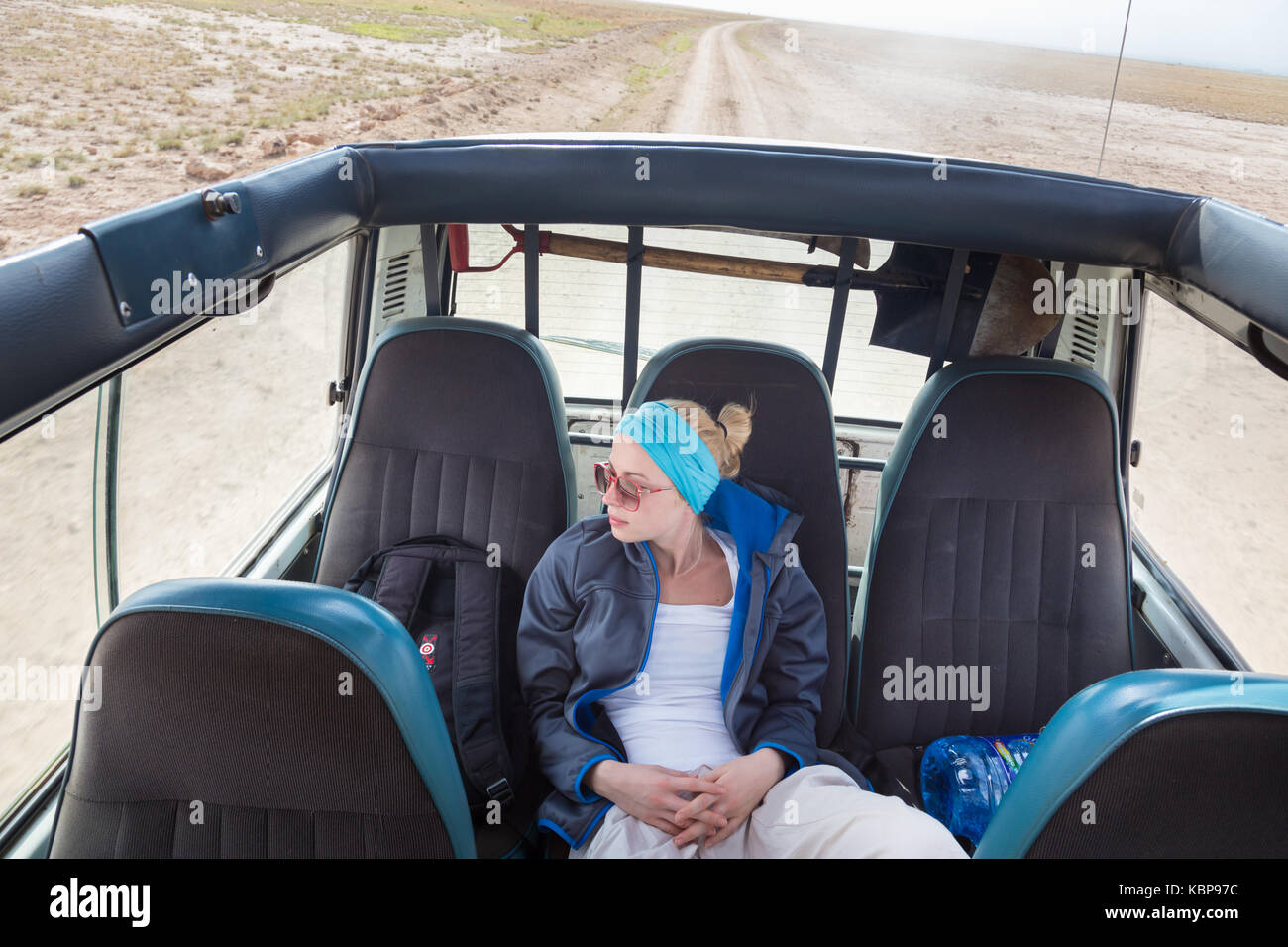 Woman on african wildlife safari observing nature from open roof safari jeep. Stock Photo