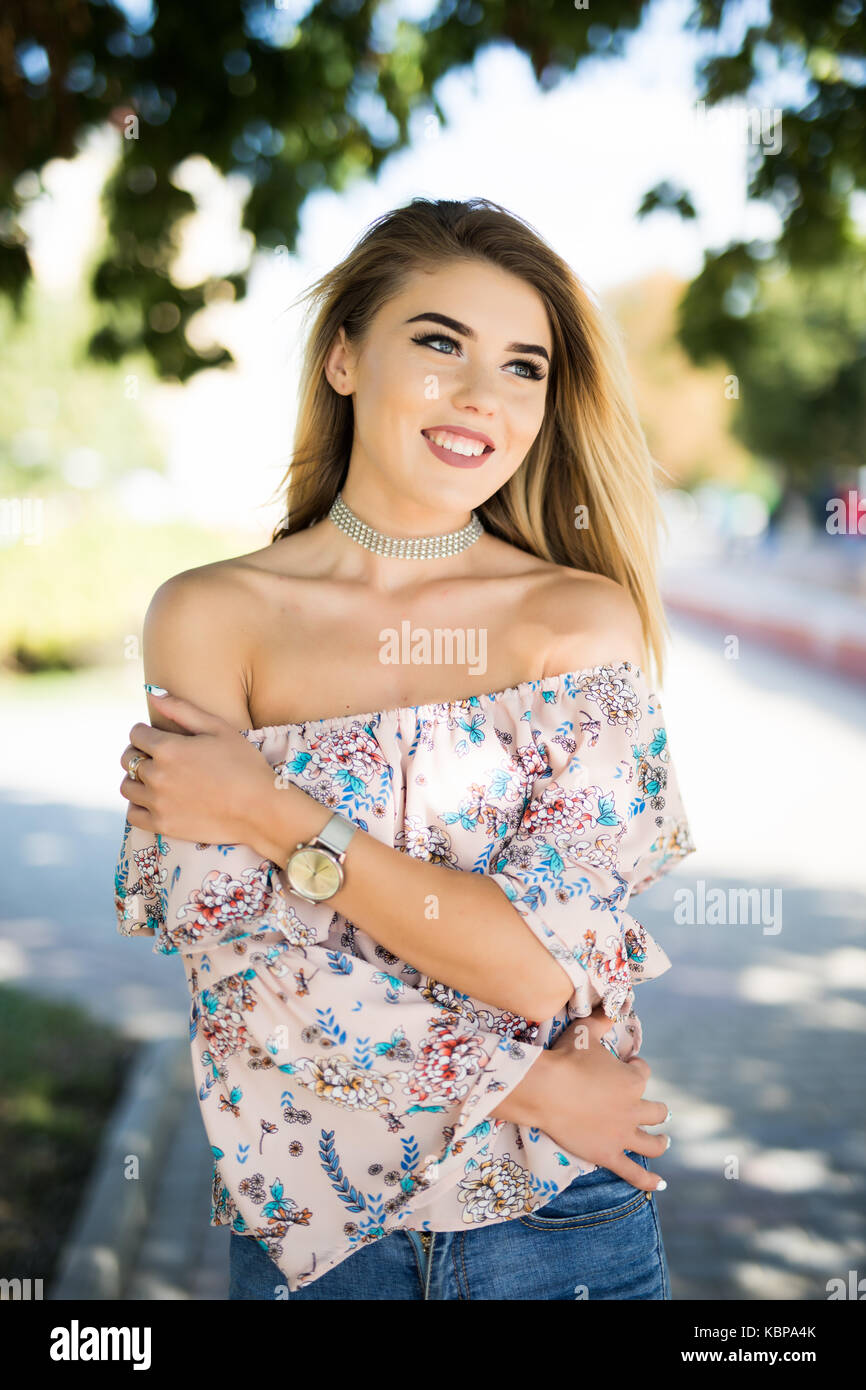 Portrait of young smiling woman in the park with green trees at summer ...