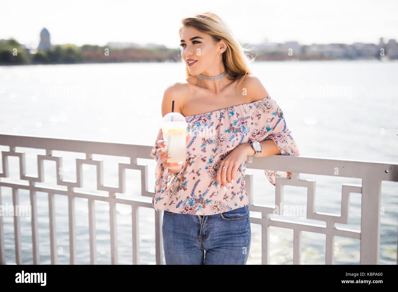 Portrait of young smiling caucasian woman with cup of cold lemonade embankment area Stock Photo