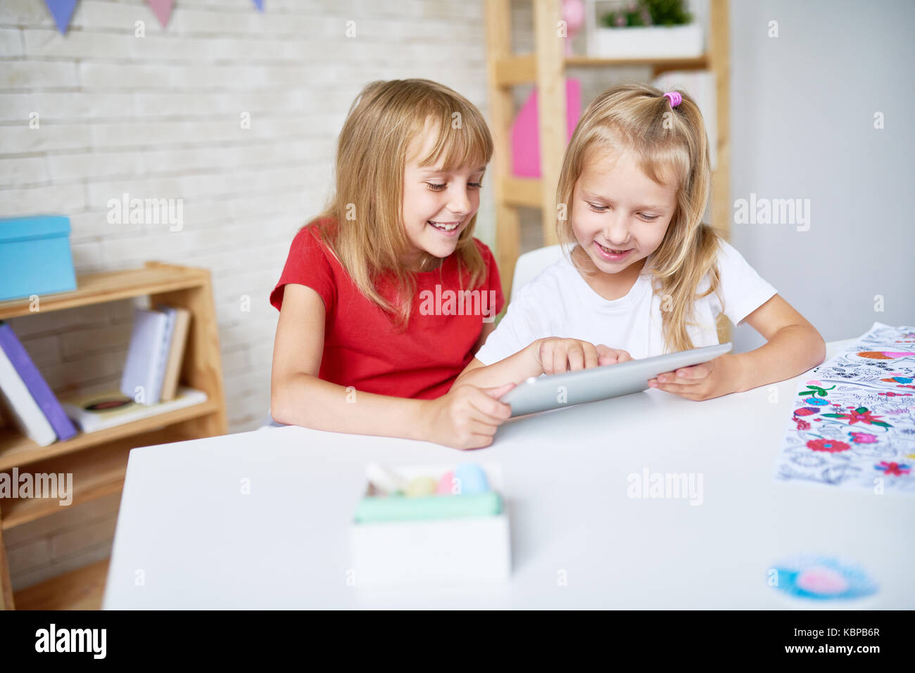 Portrait of two happy little sisters using digital tablet together and ...