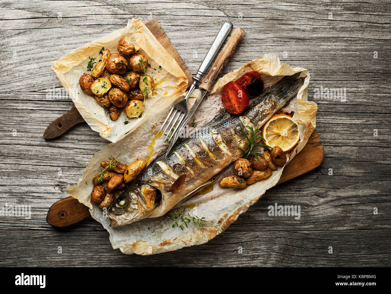 Baked sea bass with roasted potatoes on wooden table Stock Photo Alamy