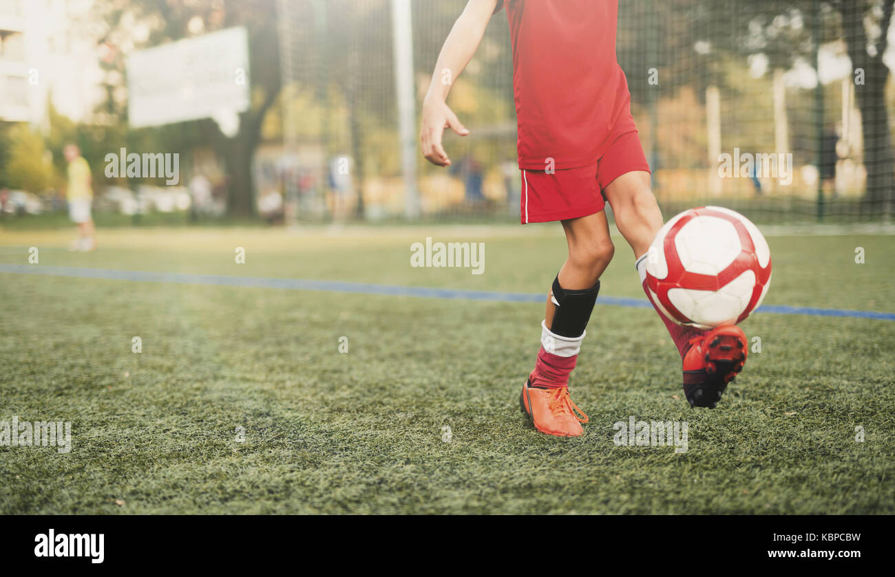 Youngster playing with soccer ball on field Stock Photo