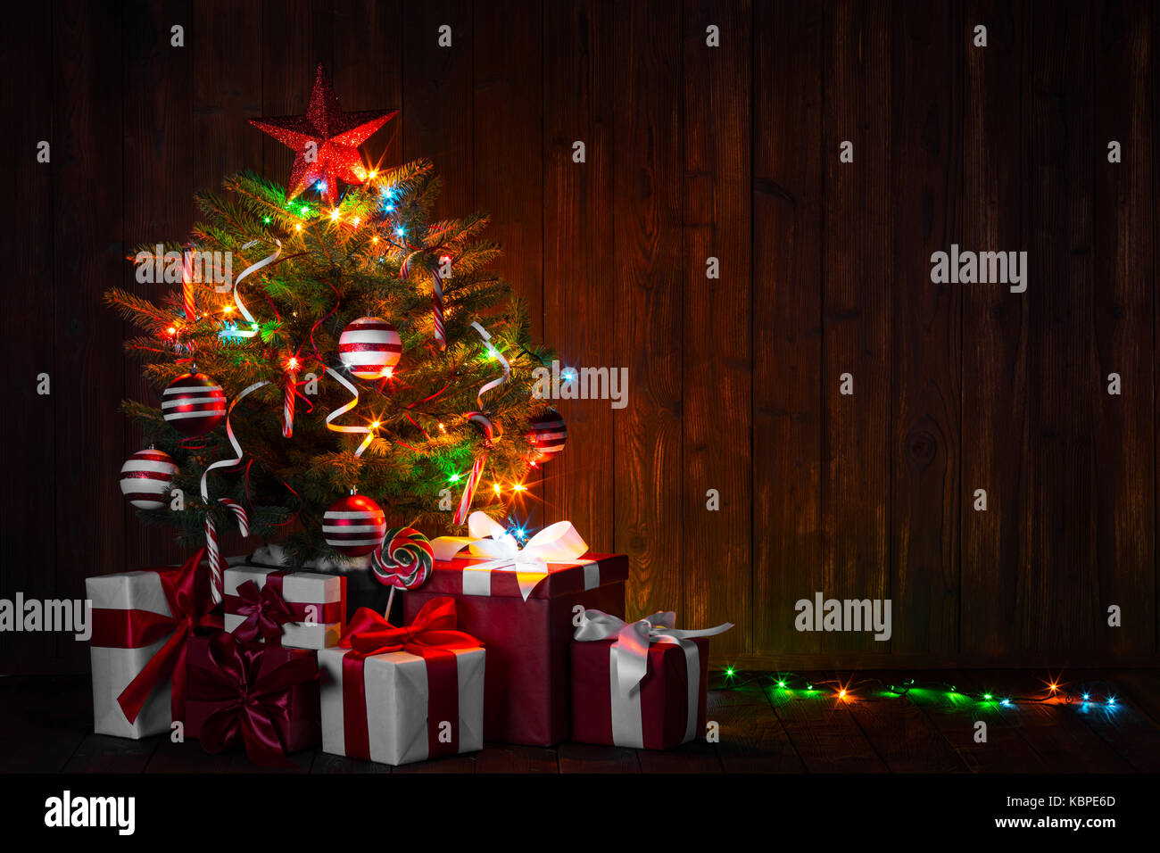 Decorated Christmas tree with glowing lights and gift boxes on wooden ...