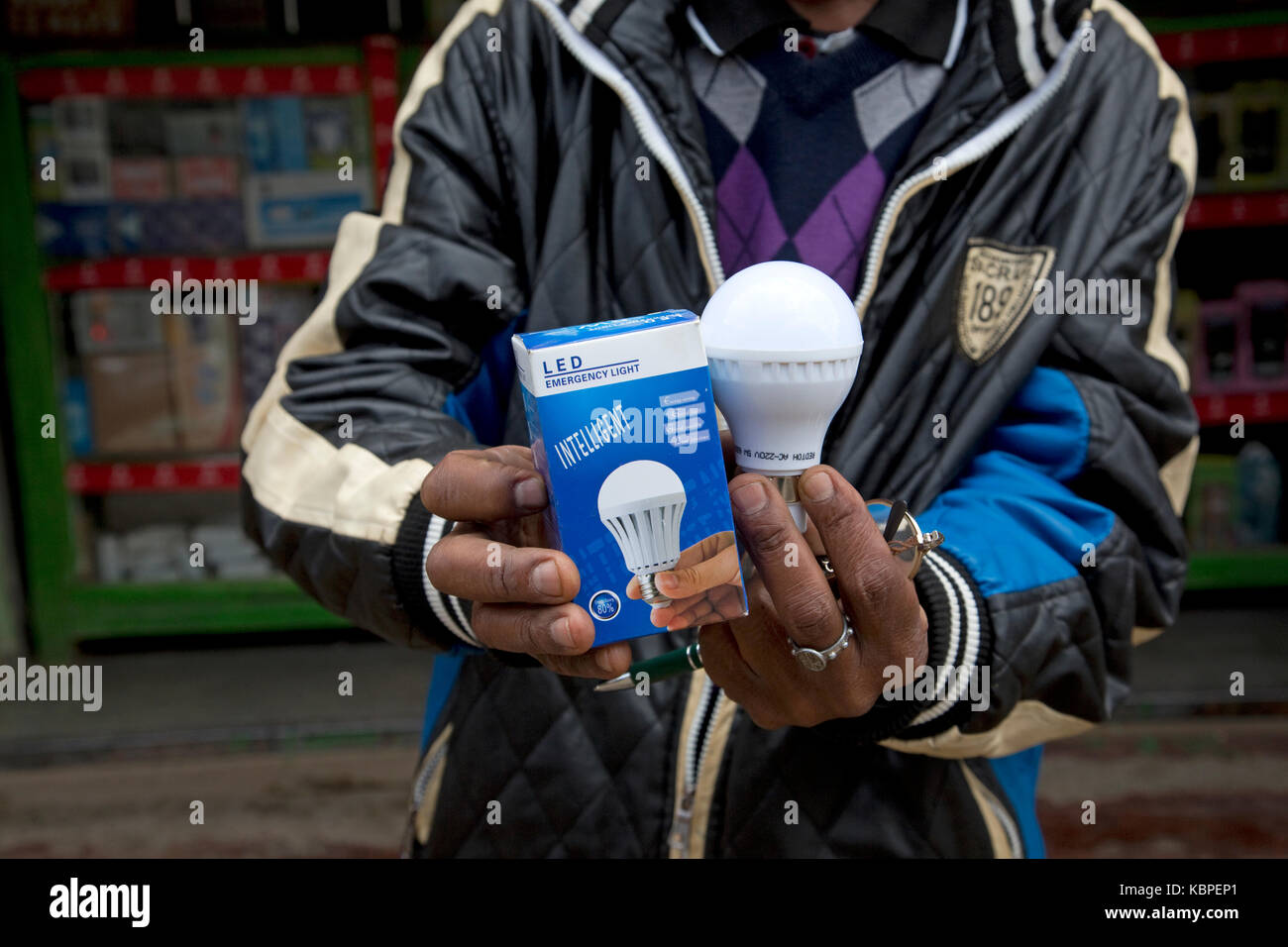 African man holding intelligent energy effiicient LED lamps outside duka in Kamere Township Kenya Stock Photo