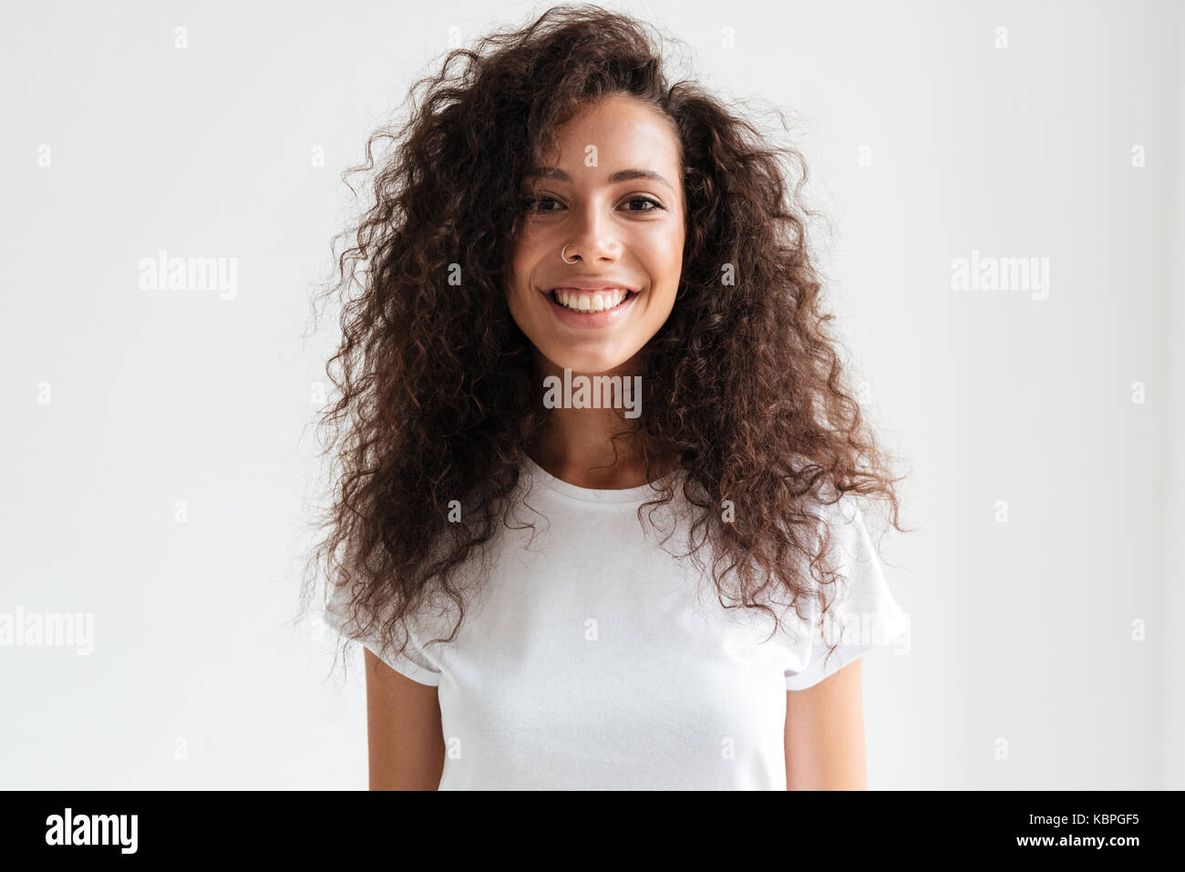 Portrait of a smiling pretty girl with long curly hair looking at ...