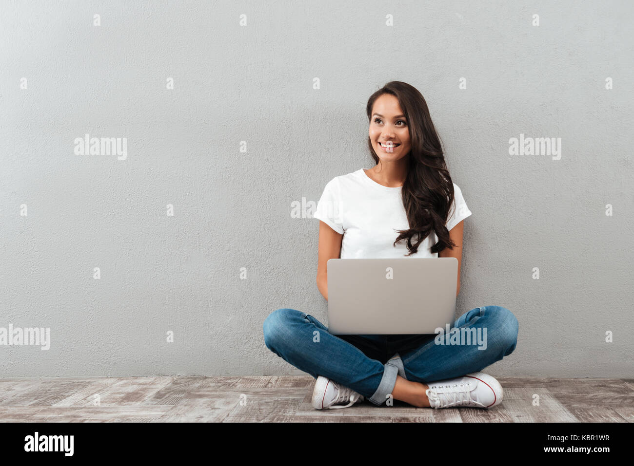 Happy cheerful asian woman working on laptop computer while sitting on ...