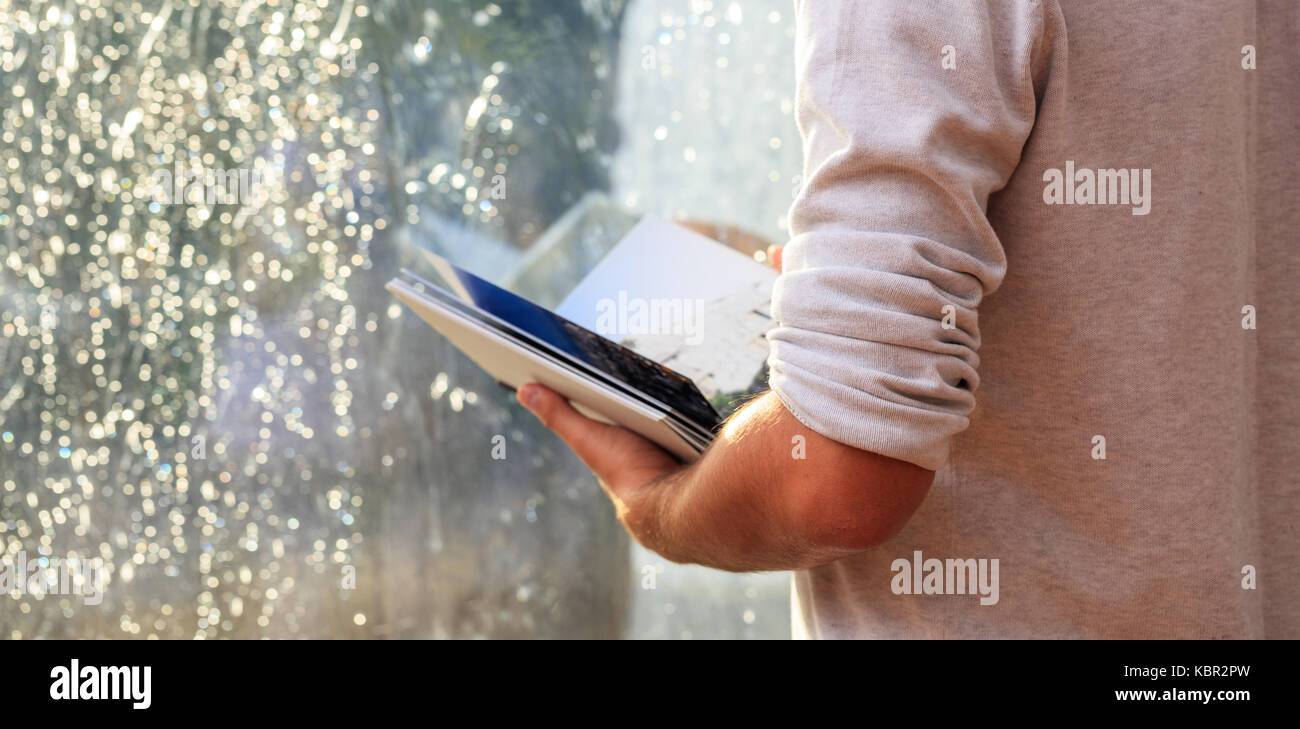 Young man holding a book infront of a glass window Stock Photo