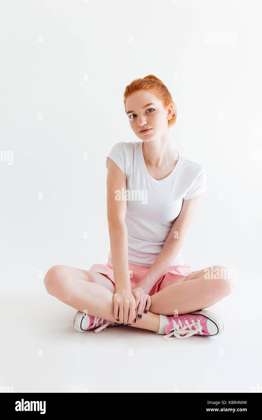 Vertical image of pretty ginger girl sitting on the floor and looking ...