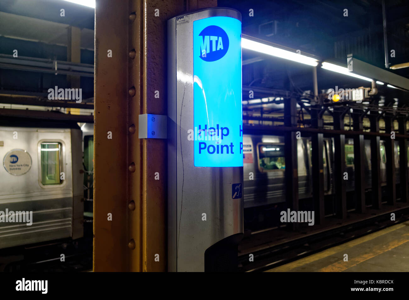 MTA emergency telephone or intercom on a subway platform with train arriving in the background. Stock Photo