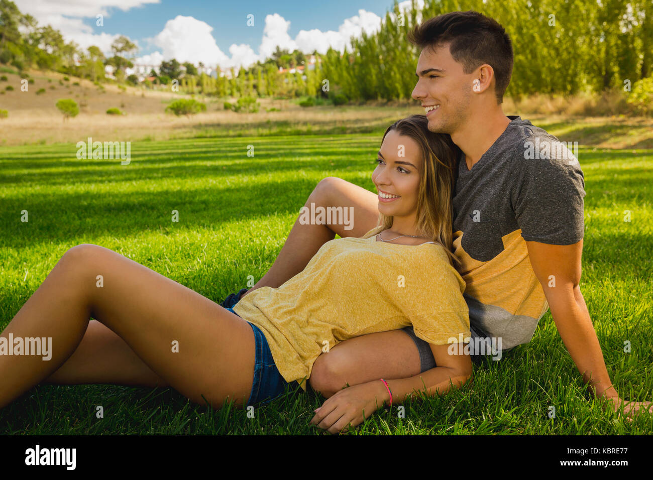 Young couple sitting on the grass and relaxing Stock Photo - Alamy