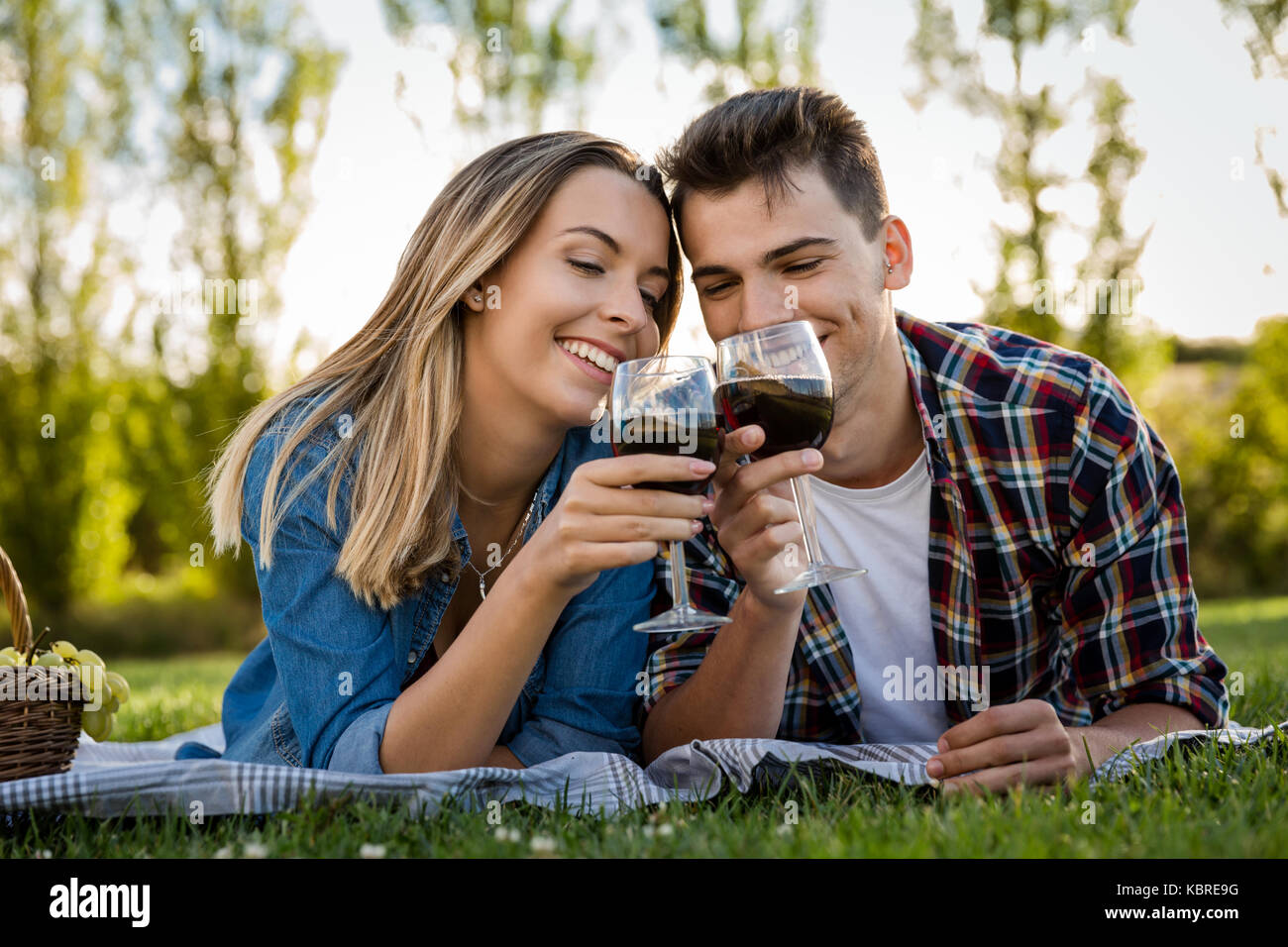 Shot of a beautiful couple on the park making a picnic and drinking ...