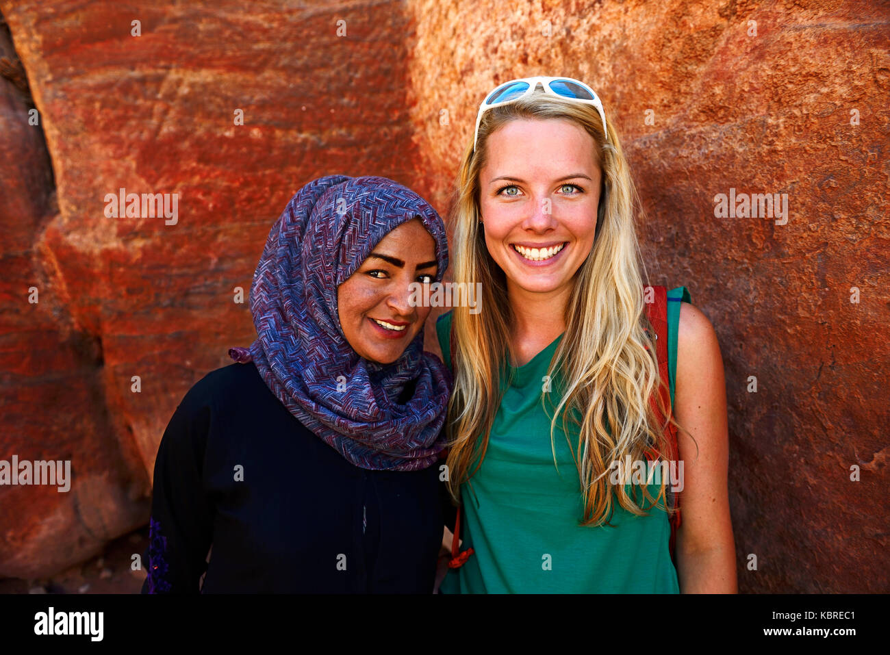 Tourist girl poses with local bedouin girl at colourful rock-formations in Petra, Wadi Musa, Jordan Stock Photo