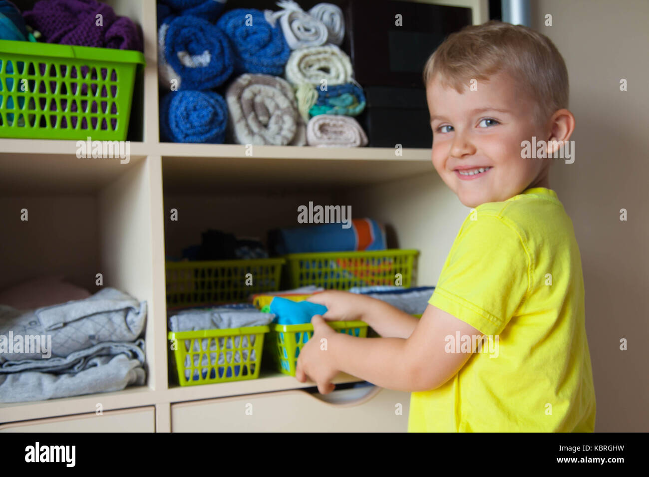 The child puts his clothes on. The boy pulls the Tshirt out of the closet Stock Photo Alamy