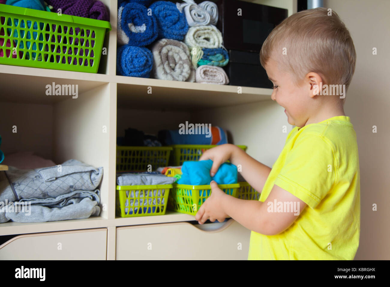 The child puts his clothes on. The boy pulls the T-shirt out of the closet. Stock Photo