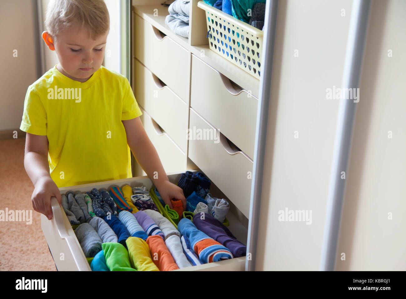 Снимают по 1 вещи. Ребенок складывает одежду. Ребенок складывает вещи в шкаф. Мальчик складывает одежду. Дети раскладывают вещи.