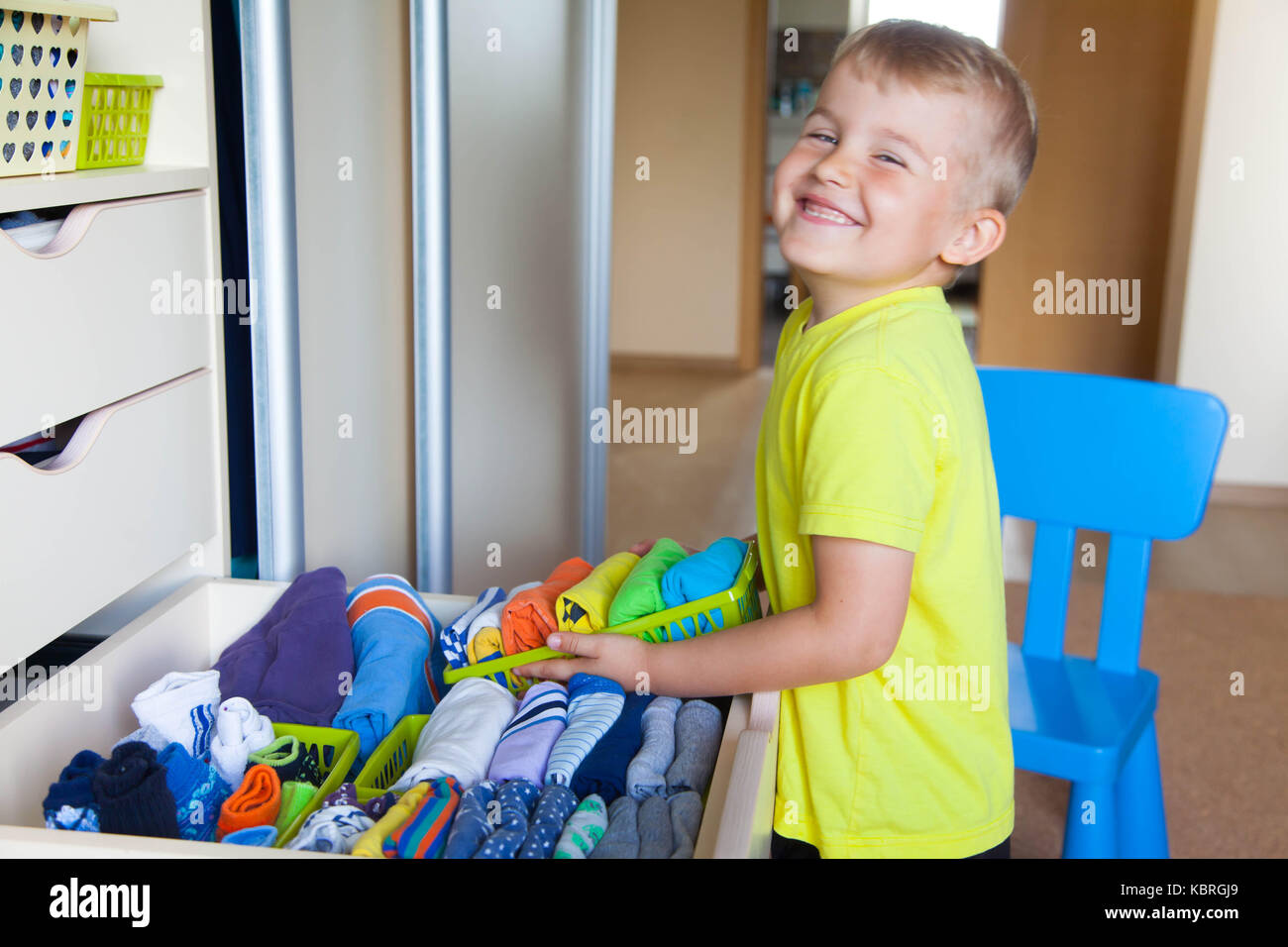 The child puts his clothes on. The boy pulls the Tshirt out of the closet Stock Photo Alamy