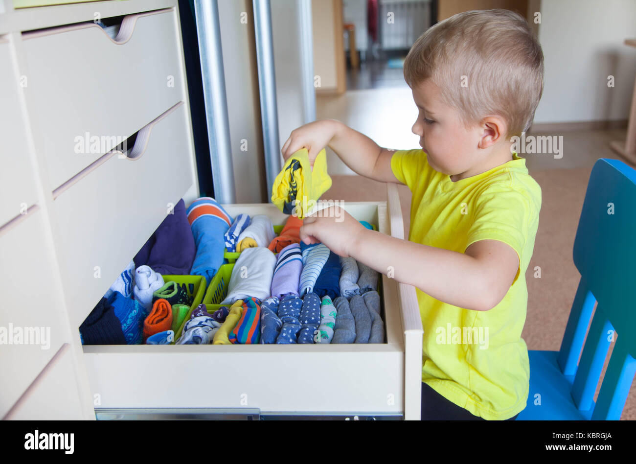 The child puts his clothes on. The boy pulls the Tshirt out of the closet Stock Photo Alamy