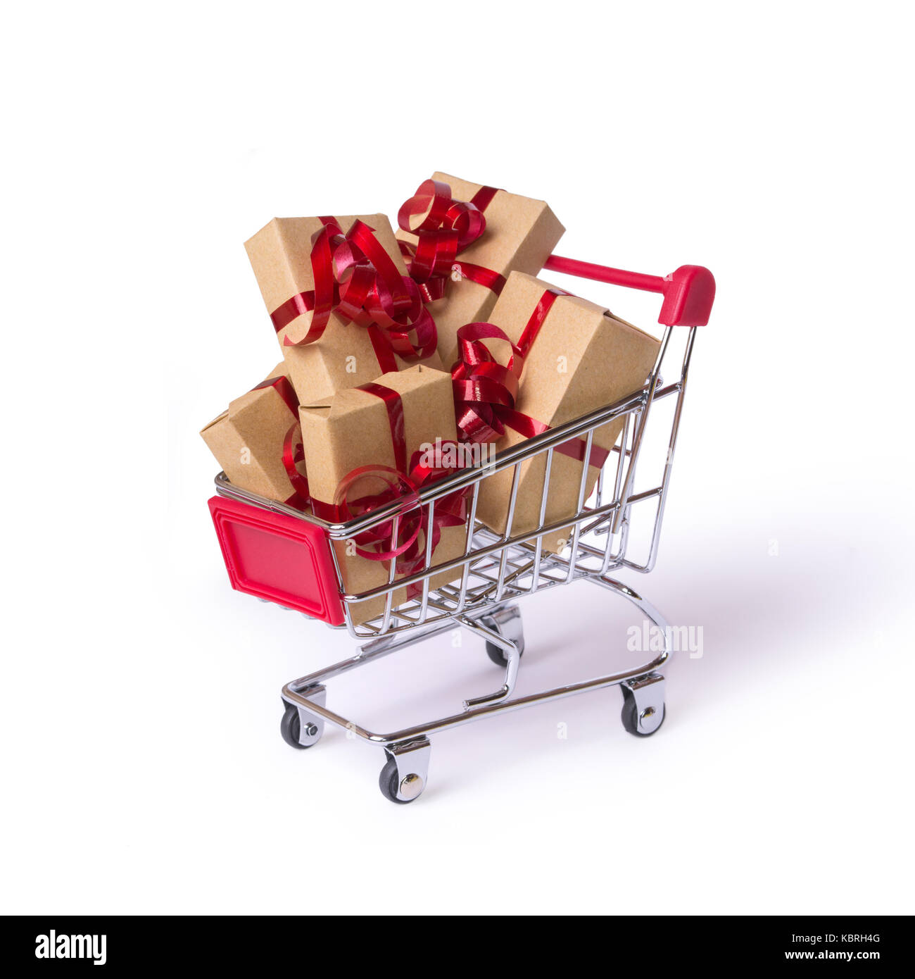 Creative concept with shopping trolley with gifts isolated on a white background. Gifts wrapped in kraft paper with a red ribbon and bow. Stock Photo