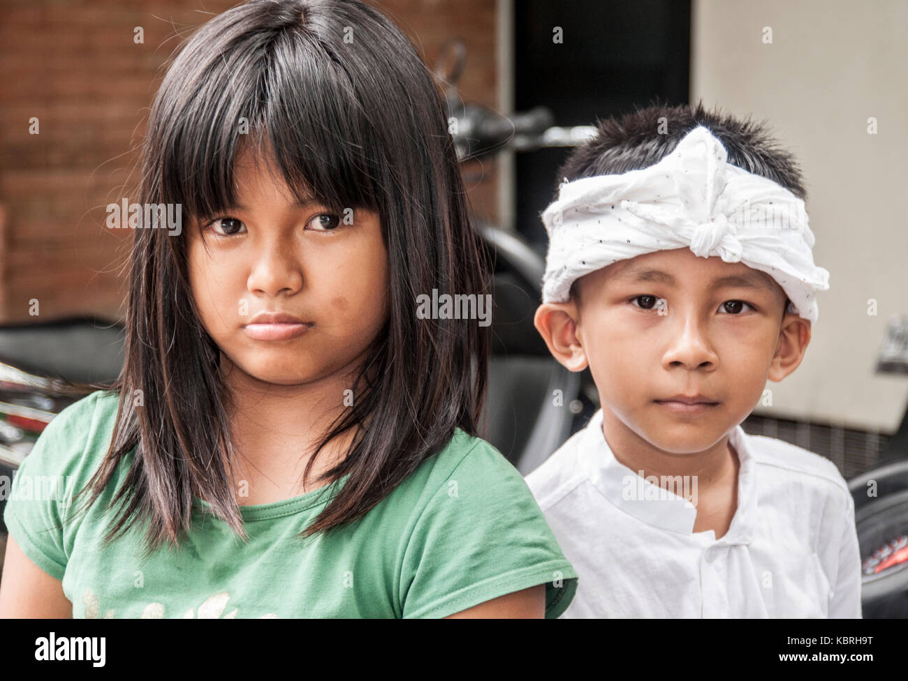 Balinese boy and girl watching a procession in Ubud, the island's cultural capital. The boy wears ceremonial costume. Stock Photo