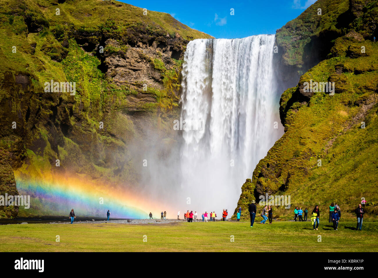 Iceland, Skogafoss waterfall with double rainbow and tourist admiring ...