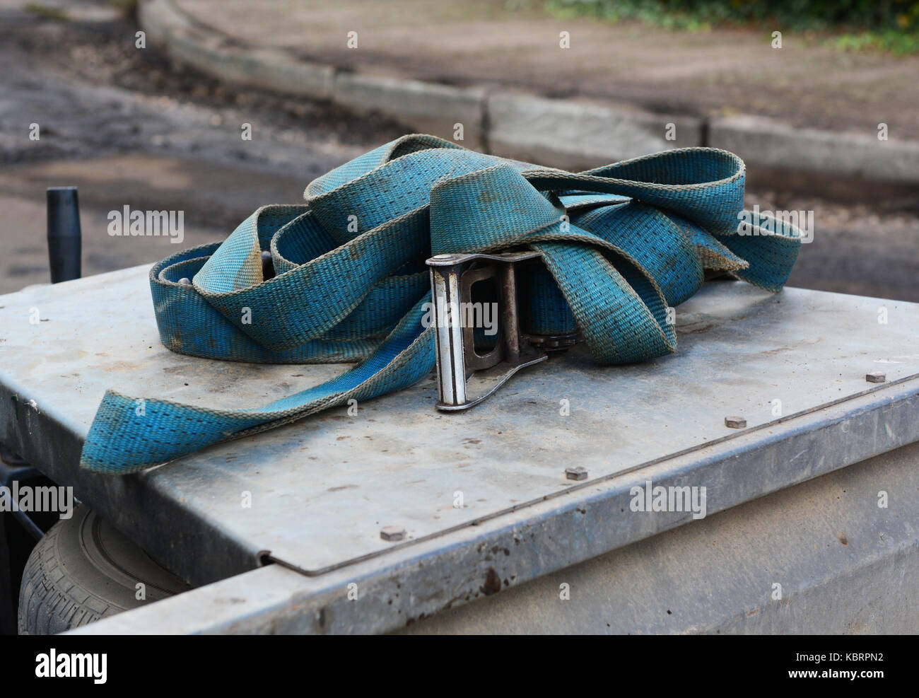 Blue nylon industrial strap with a metal buckle, piled on a metal trailer in a street undergoing repairs Stock Photo