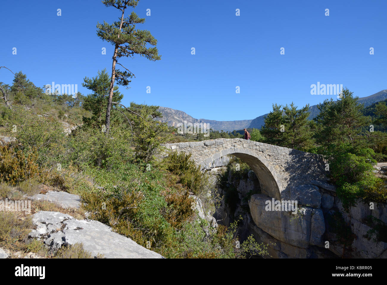 Walker Crossing Humpback Bridge, the Pont de Sautet (1787), over Jabron River, near Trigance, in the Verdon Gorge Regional Park Provence France Stock Photo