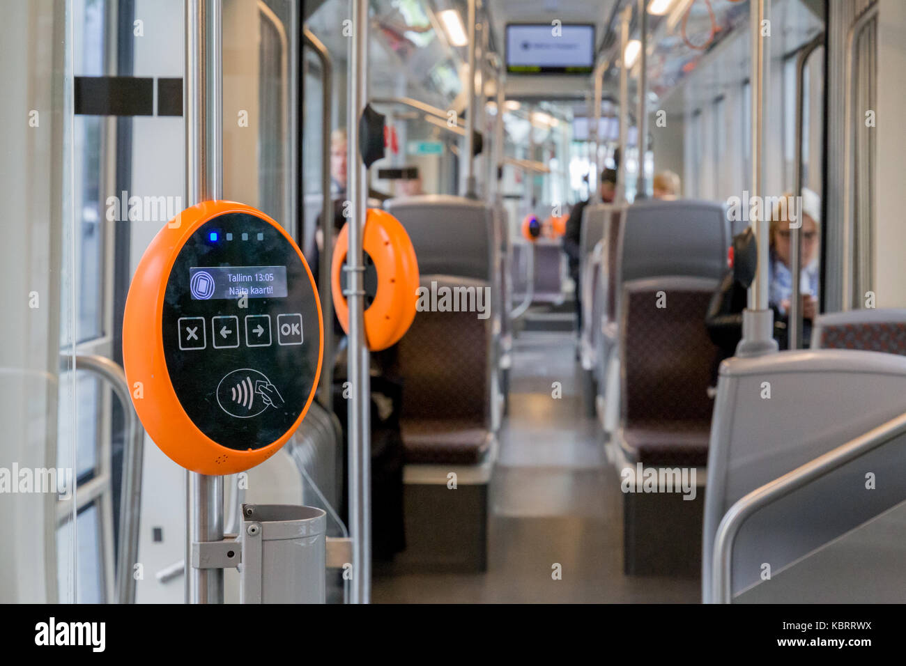Orange modern magnetic ticket validator with tram and people in background Stock Photo