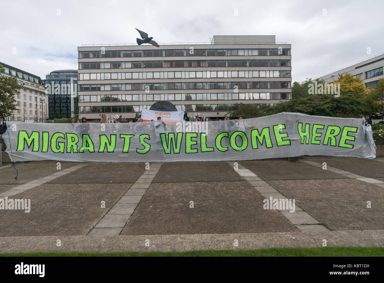 London, UK. 30th September, 2017. Protesters hold a giant banner 'Migrants Welcome Here' at the rally at St Thomas' Hospital to call for an end to immigration checks and charging of migrants for NHS services. The Migrants Welcome bloc, Maternity Care bloc and Sisters bloc met opposite the hospital and marched onto the area around the memorial to Jamaican -born Crimean War nurse Mary Seacole for a rally at which a number of testimonies of those who have suffered from these policies were read out. Credit: Peter Marshall/Alamy Live News Stock Photo