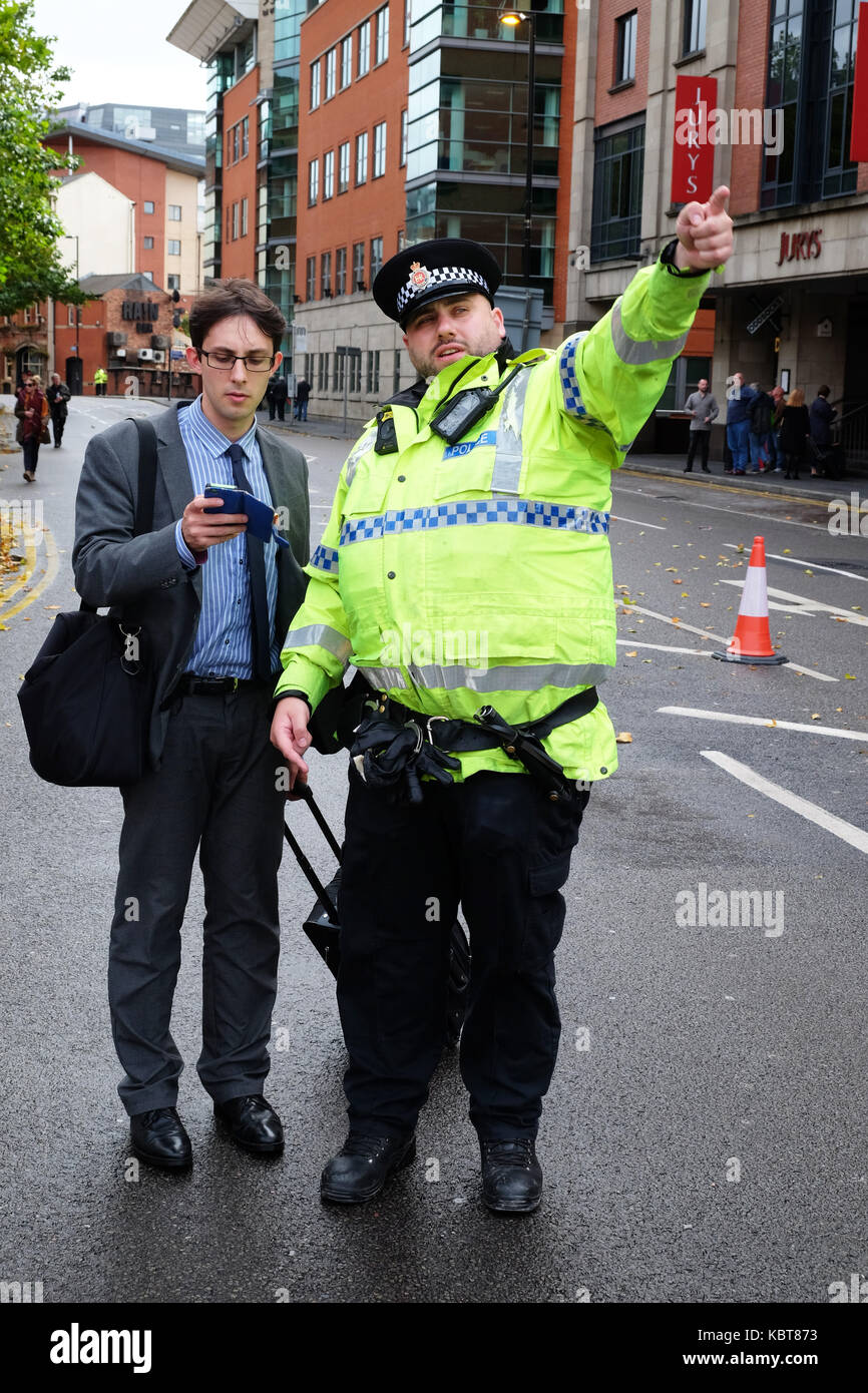 Central Manchester UK, Sunday 1st October 2017 - A Conservative Party delegate seeks directions from one of the many police officers deployed across the city on the opening day of the Conservative Party Conference. Steven May / Alamy Live News Stock Photo