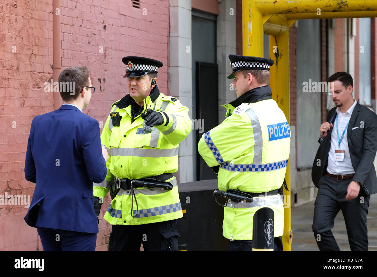 Manchester UK, Sunday 1st October 2017 - A Conservative Party delegate seeks directions from one of the many police officers deployed across the city on the opening day of the Conservative Party Conference. Steven May / Alamy Live News Stock Photo