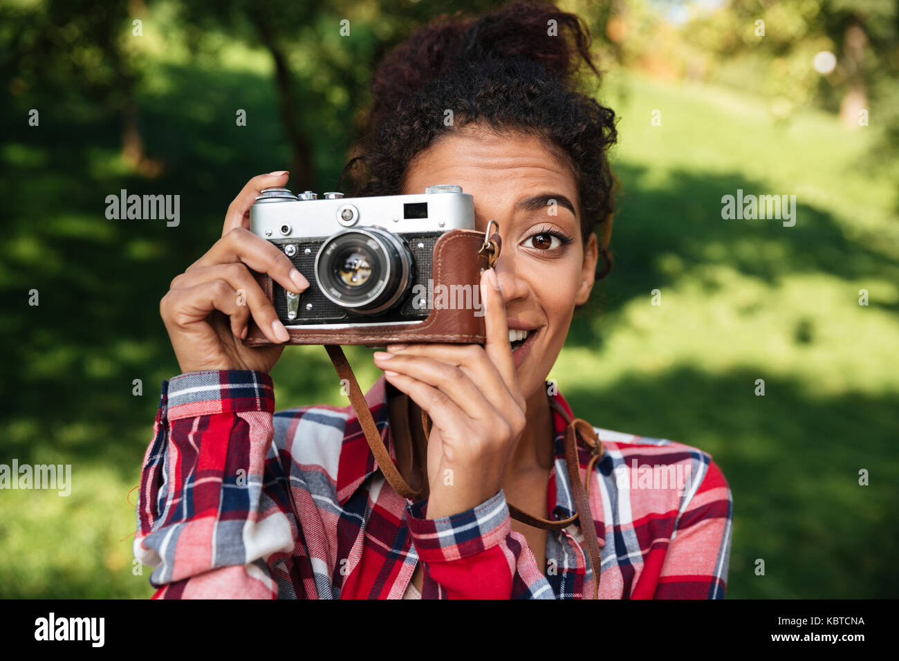 Picture of amazing young african woman photographer sitting outdoors in park. Holding camera. Stock Photo