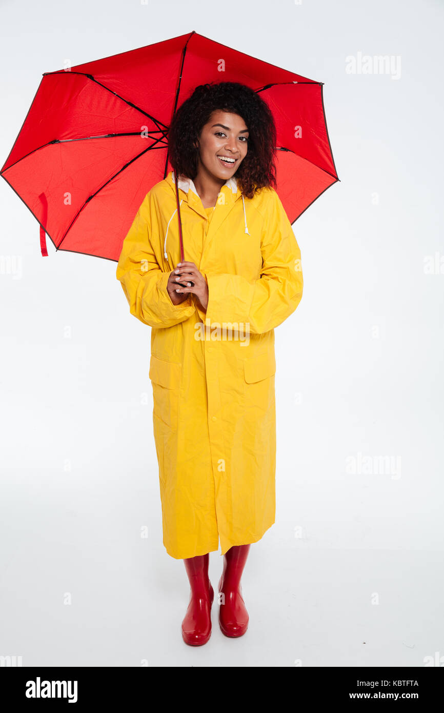 Full length image of Pleased african woman in raincoat posing with