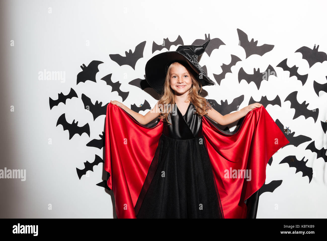 Funny little girl dressed in halloween costume posing with bats on a background Stock Photo Alamy