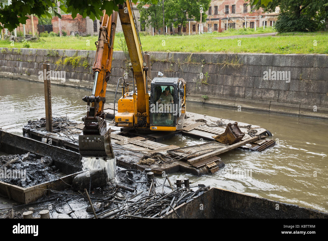 ST. PETERSBURG, RUSSIA - JULY 26, 2015: Working on the dredger clears the bottom of the canal from the scrap metal and sediment Stock Photo