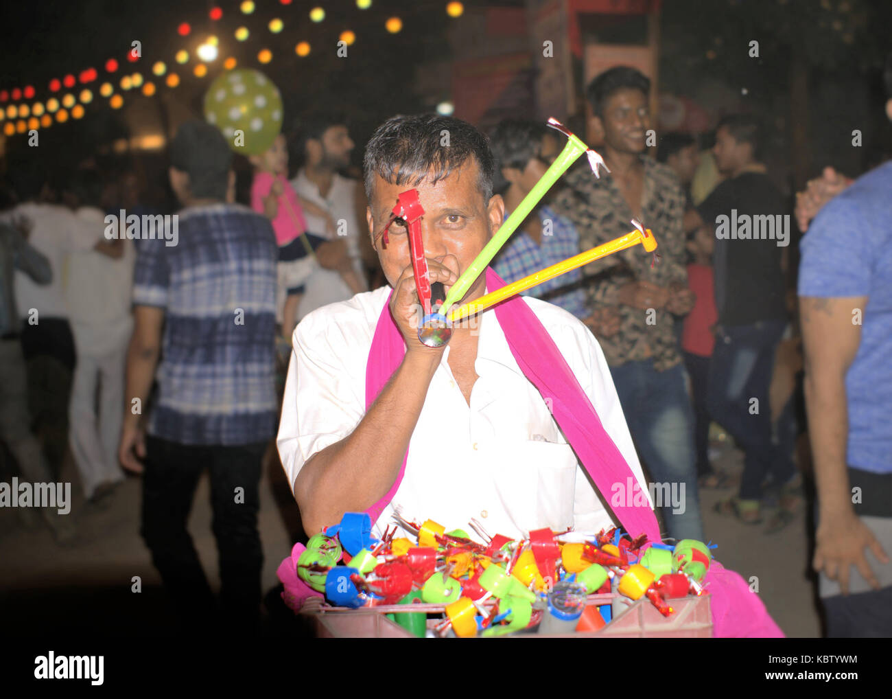 Indian Man selling toys for kids on the street of Delhi, India. People walking in background. Stock Photo