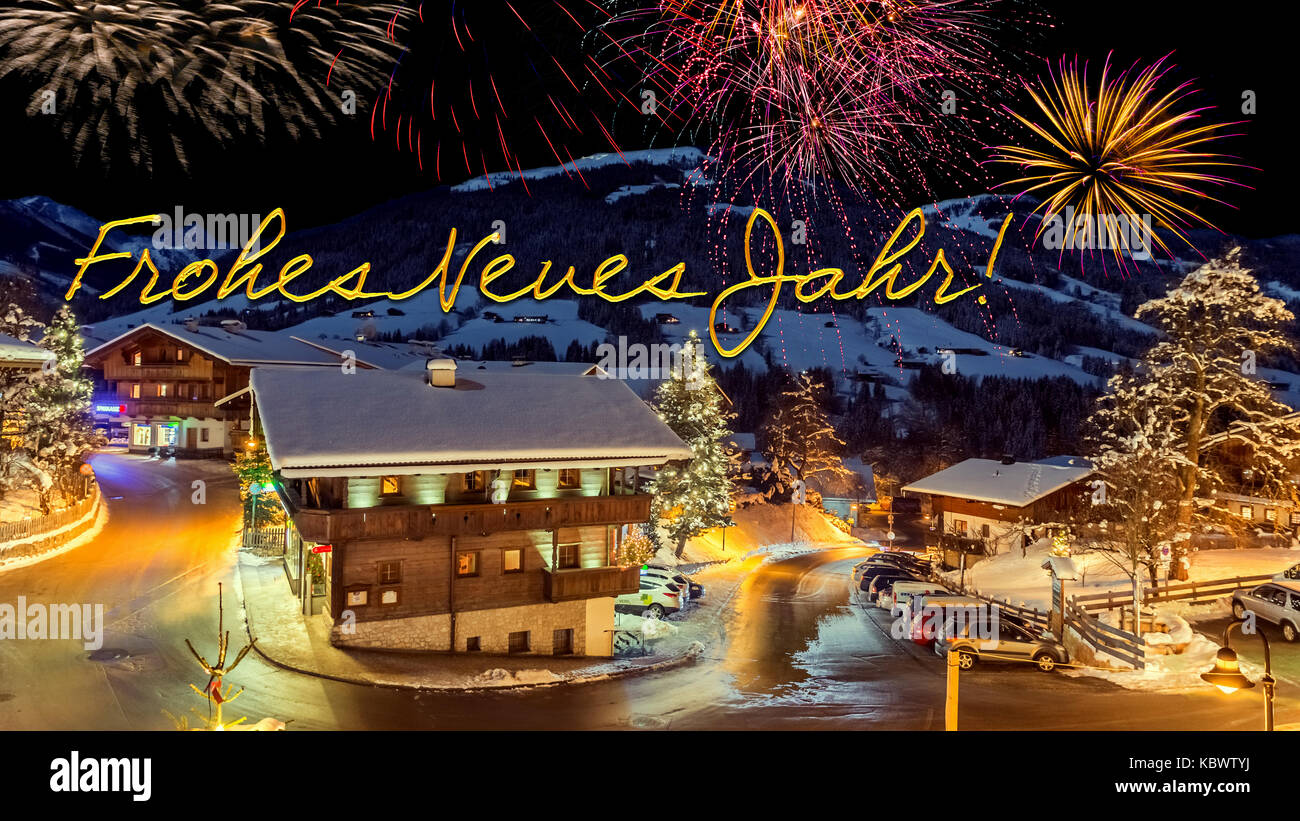 new year's eve card with alpine village in snow, fireworks, german text 'Frohes Neues Jahr!' Stock Photo