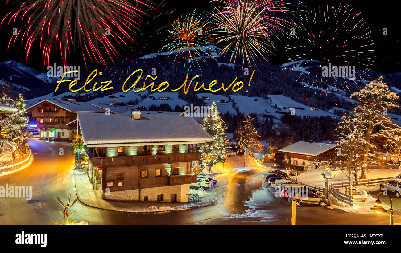 new year's eve card with alpine village in snow, fireworks, text 'Feliz Ano Nuevo!' Stock Photo