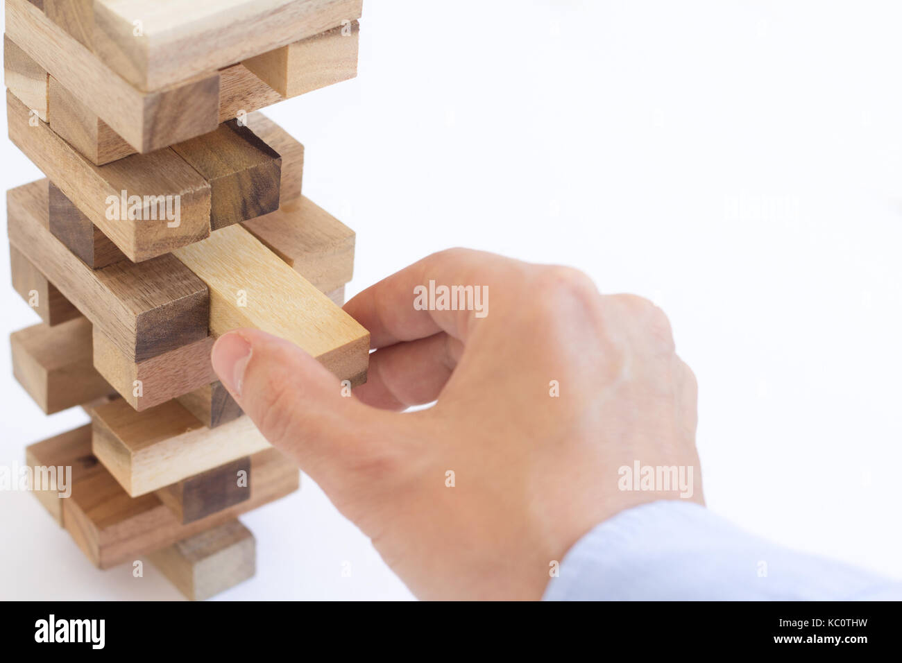 hand of businessman pulling out or placing wood block on tower Stock Photo