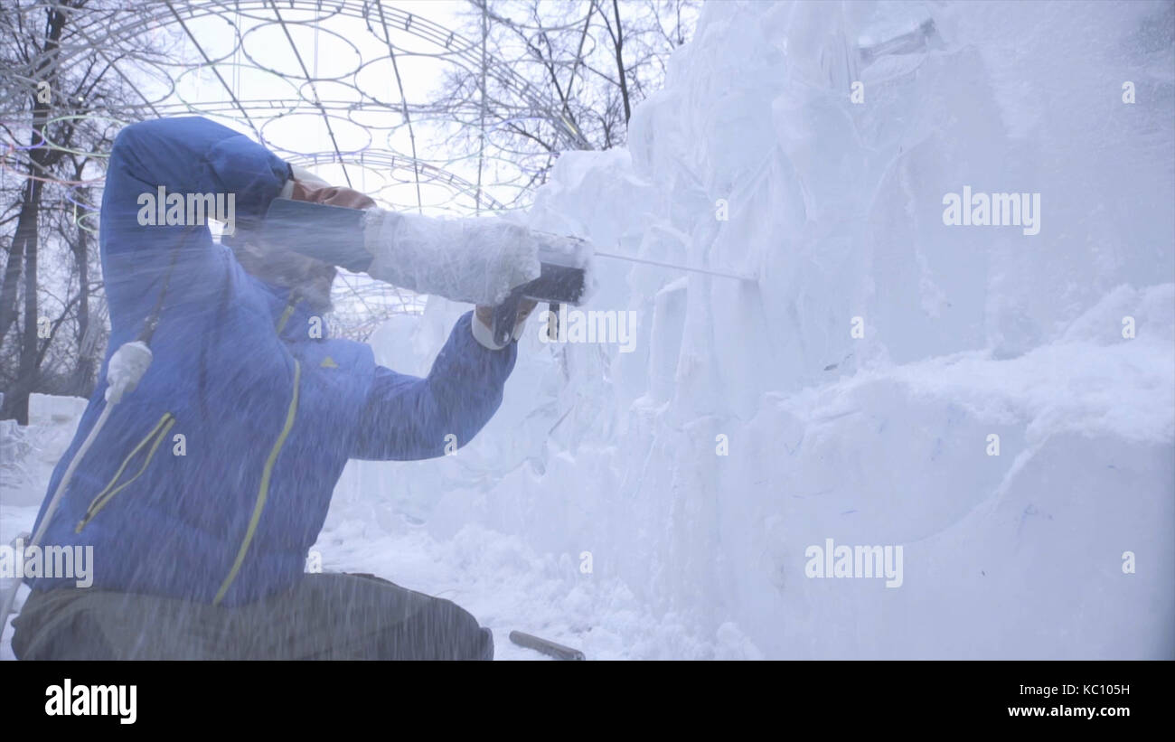 View of sculptor carving ice. Movement. Cut ice with a chainsaw. Cut ...