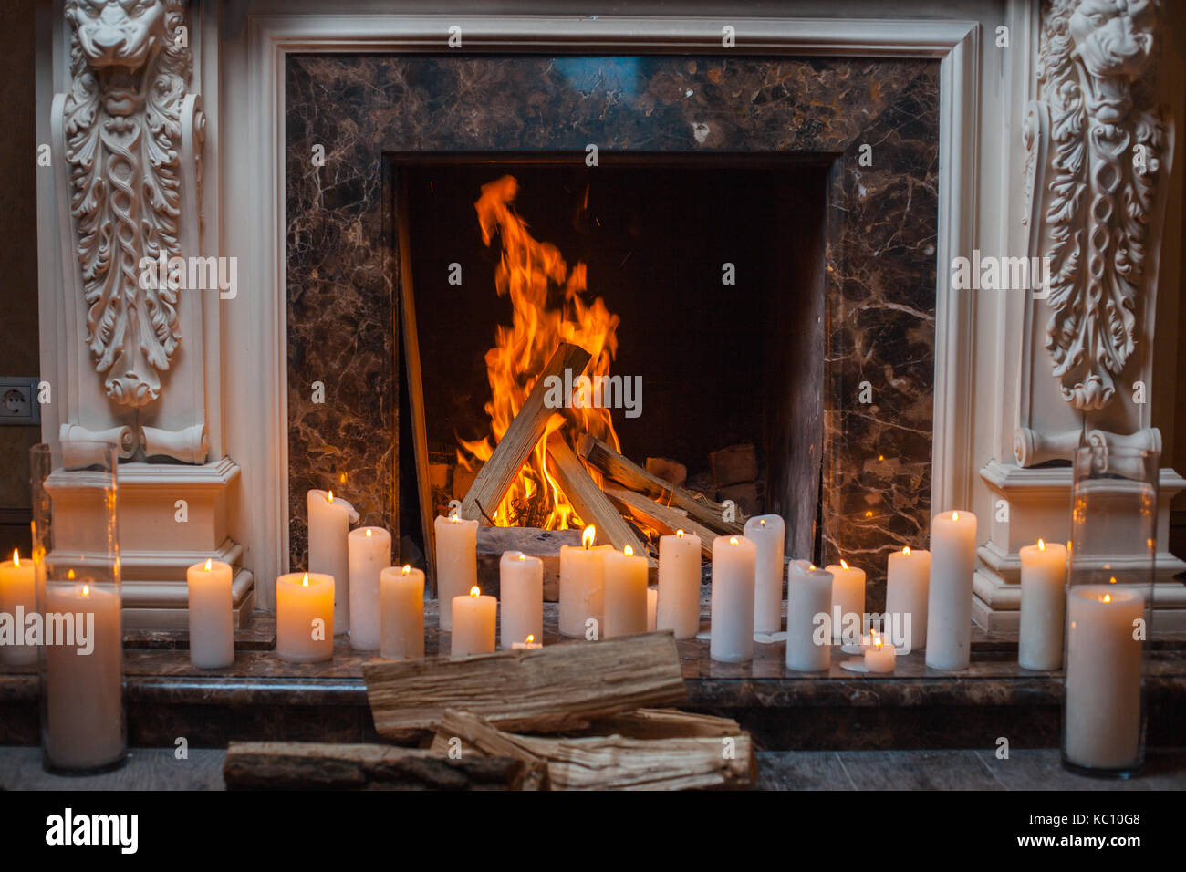 In a fireplace fire burns. Near the fireplace is a lot of burning candles Stock Photo