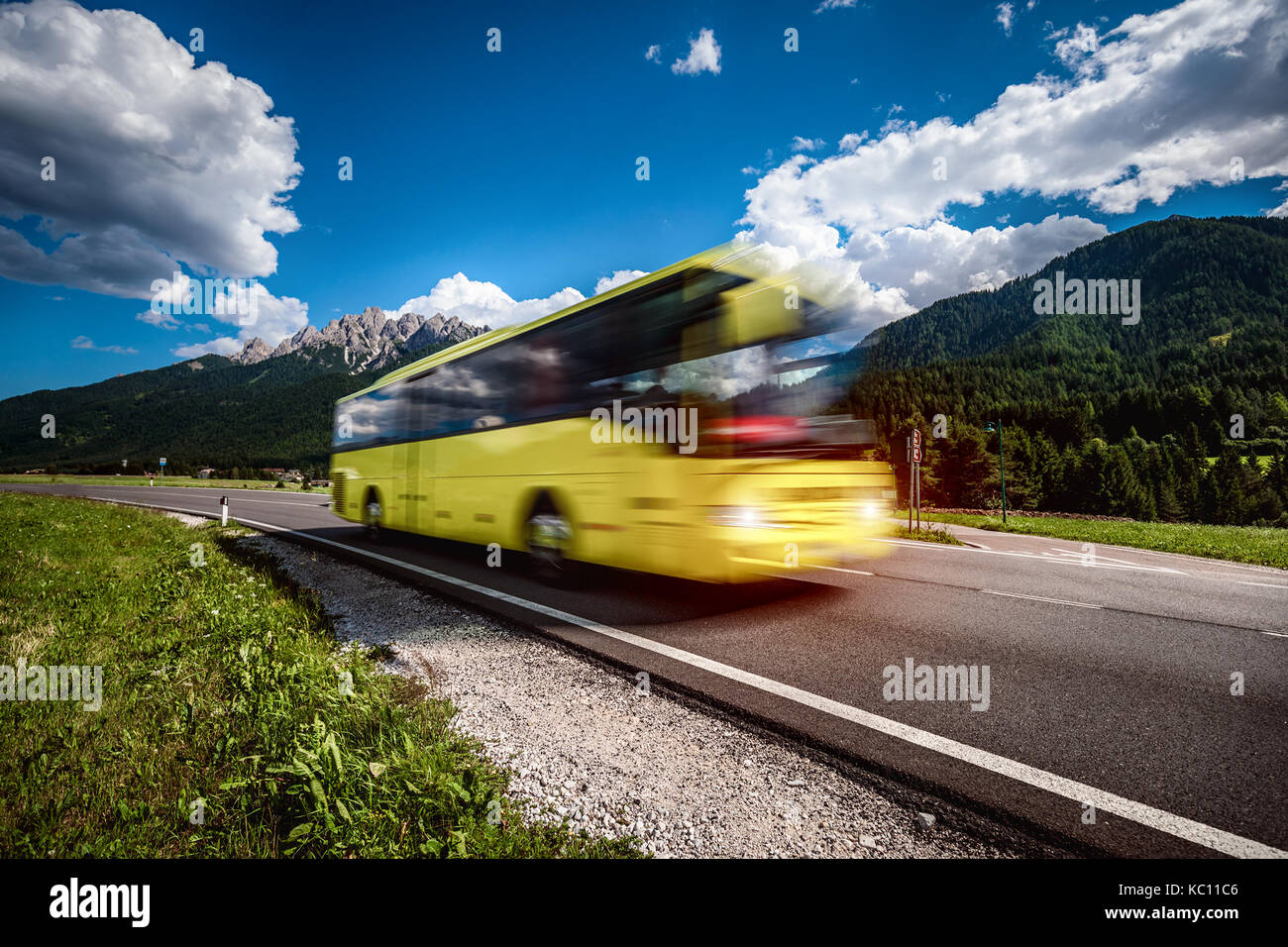 Yellow Public bus traveling on the road in the background the Dolomites Alps Italy. Public transport service. Warning - authentic shooting there is a  Stock Photo